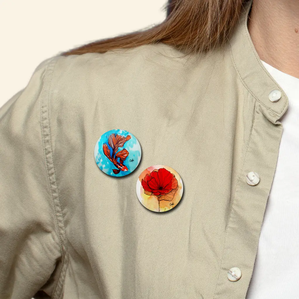 Deux badges ronds de la collection "entre faune et flore" portés en situation sur une chemise de femme, badges / pins / broches